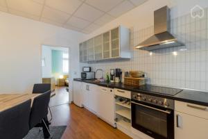 ベルリンにあるSpacious and modern furnished apartment for 10 guestsのキッチン(白いキャビネット、テーブル、コンロ付)