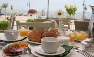 a table with plates of food and cups of orange juice at Makedos Sea View in Nea Vrasna