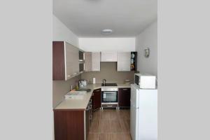 a kitchen with a white refrigerator and brown cabinets at Pláza Apartman - city center, free parking, free wifi in Debrecen