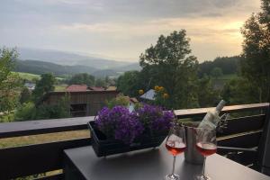 a table with two glasses of wine and a basket of flowers at Apartment Tälerblick 2 in Böbrach