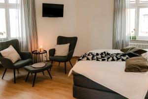 a bedroom with a bed and two chairs and a tv at Little Loft Limburg in Limburg an der Lahn