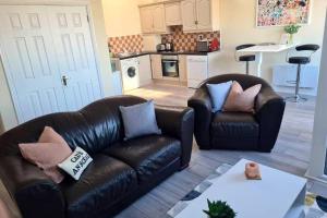 a living room with two leather couches and a kitchen at Number 10 in Dungarvan