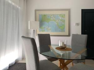 een eetkamer met een glazen tafel en stoelen bij CasaBlanca - Haus am Meer in Fuzeta +24 foto's