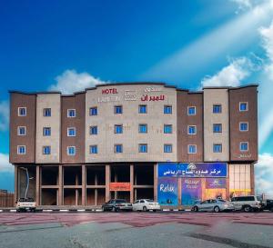 un grand bâtiment avec des voitures garées devant lui dans l'établissement فندق لامير إن Lamer in Hotel, à Sharurah
