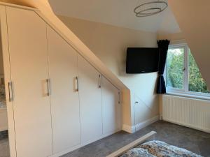 a room with white cabinets and a tv on the wall at The Croft in Sandhurst
