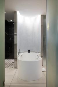a white bath tub in a bathroom with a mirror at The Capital 15 on Orange Hotel & Spa in Cape Town