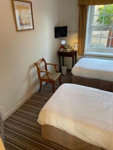 a bedroom with a bed, chair, desk and window at Corncroft Guest House in Witney