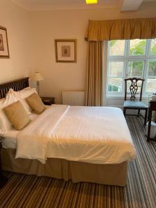 a hotel room with a bed, chair, table and window at Corncroft Guest House in Witney