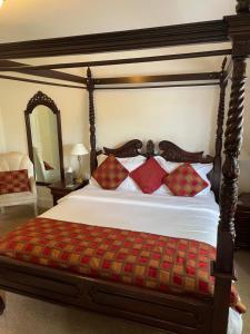 a bedroom with a large bed with red pillows at Corncroft Guest House in Witney