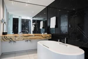 a bathroom with a tub and a large mirror at The Capital 15 on Orange Hotel & Spa in Cape Town