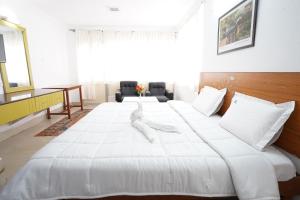 a large white bed with white sheets and pillows at Hotel TamilNadu - Yercaud in Yercaud