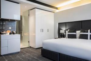 a bedroom with a large white bed and a walk in shower at The Capital 15 on Orange Hotel & Spa in Cape Town