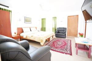 a living room with a bed and a chair at Hotel TamilNadu - Yercaud in Yercaud