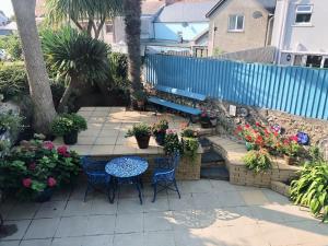 Un patio con mesa y sillas y flores. en Stunning & spacious house in central Tenby, en Tenby