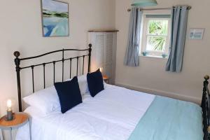 1 dormitorio con 1 cama con sábanas blancas y almohadas azules en Stunning & spacious house in central Tenby, en Tenby 14 fotos más