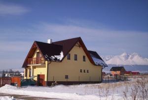 a house in the snow with mountains in the background at Penzion Tatry in Veľká Lomnica