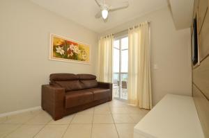 una sala de estar con una silla marrón y una ventana en Agua Azul, Condomínio com Ótima infraestrutura a uma quadra da Praia Brava N396, en Florianópolis