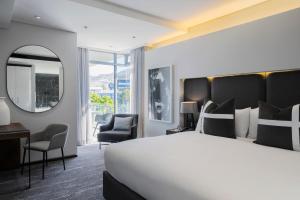 a hotel room with a large bed and a mirror at The Capital 15 on Orange Hotel & Spa in Cape Town