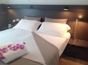 Una cama grande con sábanas blancas y peluches rosados. en Hotel Ruhig, en Marotta