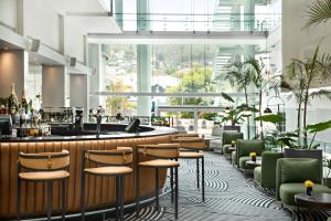 a bar in a hotel lobby with green chairs at The Capital 15 on Orange Hotel & Spa in Cape Town