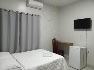 ein kleines Schlafzimmer mit zwei Betten und einem Fernseher in der Unterkunft AMAZONIA HOTEL in Colíder