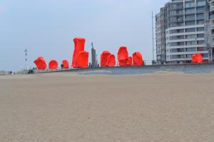 a group of red sculptures on the beach at Studio 24 Oostende in Ostend