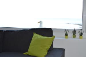 - un canapé noir avec un oreiller jaune à côté d'une fenêtre dans l'établissement Studio 24 Oostende, à Ostende
