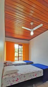 a bedroom with two beds and a ceiling fan at Recanto da Madre in Guarda do Embaú