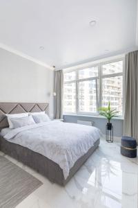 ein weißes Schlafzimmer mit einem großen Bett und großen Fenstern in der Unterkunft Arcadia romantic view in Odessa