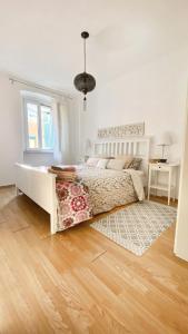 a white bedroom with a bed and a wooden floor at Apartment Evelina in Pula