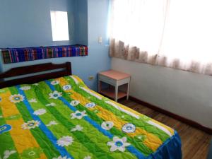 1 dormitorio con 1 cama con edredón verde y amarillo en Hostal Yumbo Imperial, en Quito