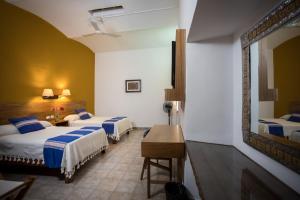 a hotel room with three beds and a desk at Parador San Agustin in Oaxaca City