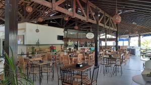 a restaurant with tables and chairs and a clock at Apartamento Wembley Tenis - H402 in Ubatuba