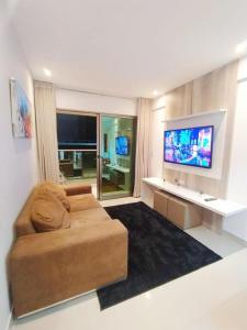 a living room with a couch and a flat screen tv at Premium Flat Praia Calma - PontaNegra in Natal