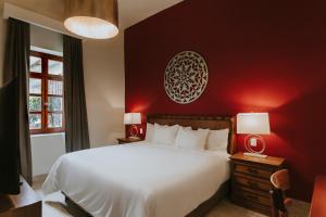 1 dormitorio con cama blanca y pared roja en Dos Patios Querétaro Curamoria Collection, en Querétaro