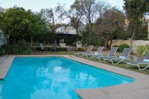 a swimming pool with two lawn chairs and two lounge chairs at LA RÉVERIE in Franschhoek