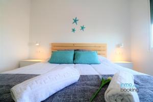 1 cama grande con sábanas blancas y almohadas azules en SUNDBEACH RODAS CLIMATIZADO WIFI Y VISTAS AL MAR, en Salou