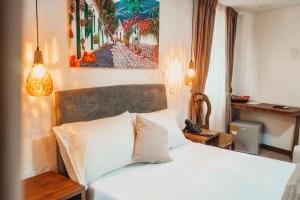 Un dormitorio con una cama blanca y una pintura en la pared en Hotel Boutique Casa del Hidalgo, en Cali