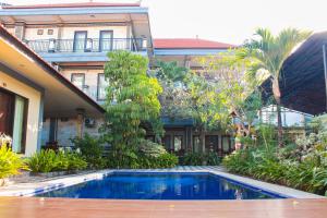 a hotel with a swimming pool in front of a building at Putu Guest House 2 in Canggu