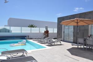 - une piscine avec des chaises et un parasol dans un bâtiment dans l'établissement Villa Cástor, à Playa Blanca