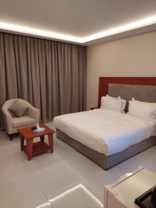 a hotel room with a bed and a chair at المهيدب 3 للشقق المخدومة - اقتصادى in Buraydah