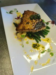 un plato blanco con un trozo de pescado y judías verdes en The Cornishman Inn en Tintagel