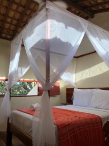 a bedroom with two beds with a mosquito net at Pousada Vila Sergipana in Barra dos Coqueiros