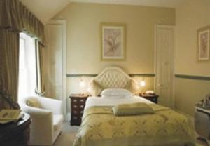 a bedroom with a bed and a chair and a window at La Fleur De Lys in Shaftesbury