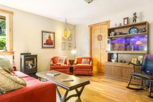 sala de estar con sofá rojo y sillas en Stray Cat Cottage, en Freeland