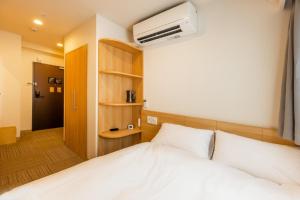 1 Schlafzimmer mit einem weißen Bett und Klimaanlage in der Unterkunft HOPETREE Tennoji in Osaka