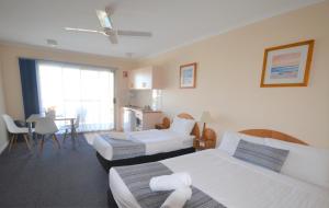 a hotel room with two beds and a television at South Seas Motel in Merimbula