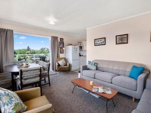 ein Wohnzimmer mit einem Sofa und einem Tisch in der Unterkunft Central Riverside Retreat - Taupo Holiday Home in Taupo