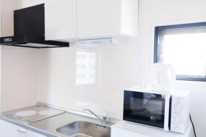 a kitchen with a microwave and a sink at The Light Inn - Vacation STAY 94696 in Tokyo