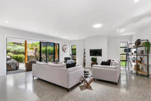 a living room with two couches and a table at Stylish Villa Escape - Matakana Holiday Home in Matakana